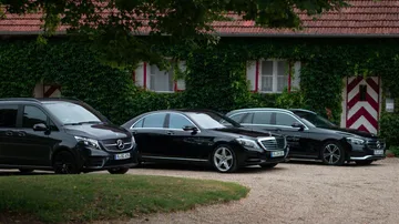 Three Mercedes cars parked on gravel driveway.