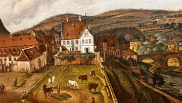European town with white house, cows grazing.