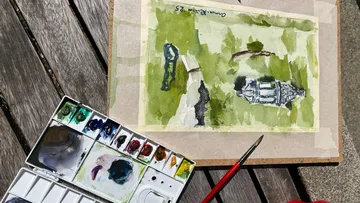 Aquarellbild und Palette auf Holztisch.