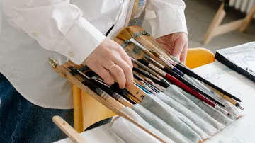 Hände halten Pinsel in einem Studio.