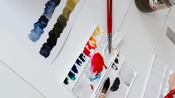 Farbpalette mit Pinseln auf einem Tisch.