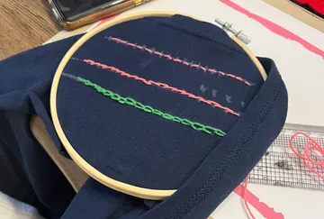 Stickrahmen mit besticktem Stoff auf Tisch.