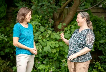 Two women conversing in a garden.
