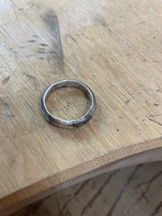 Metallring liegt auf einer Holzarbeitsbank.
