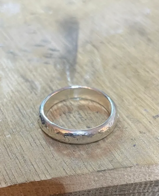 Silberring liegt auf Holzoberfläche.