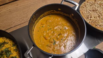 Topf mit Curry auf Holztisch.