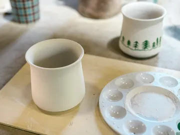 Keramiktassen auf Tisch mit Farbpalette.