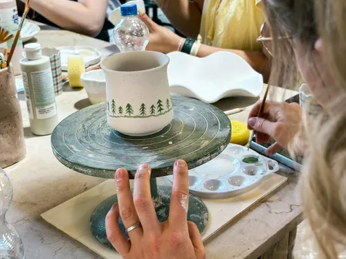 Person painting mug on pottery wheel.