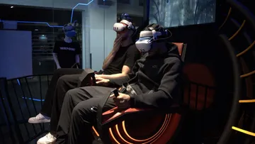 People wearing VR headsets, seated indoors.