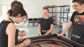 Menschen erstellen Kunst an einem Spinntisch drinnen.