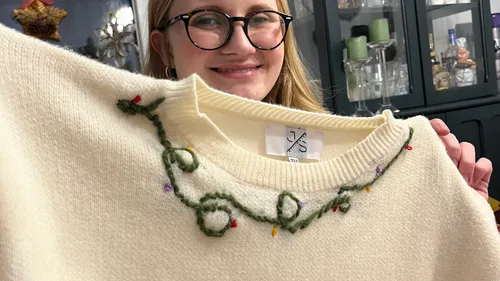 Person holding a cream sweater indoors.