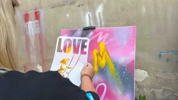 Künstler sprayt bunte Leinwand im Freien.