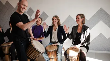 Gruppe spielt Drums, lächelt drinnen.