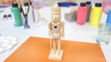 Wooden nutcracker standing on craft table.