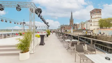 Terrace with tables, chairs, river view.