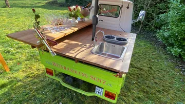 Mobiler Tresen mit Gläsern auf Wiese.