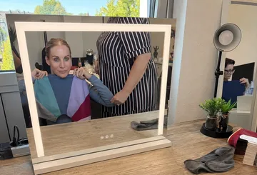 Woman holding color chart in salon mirror.