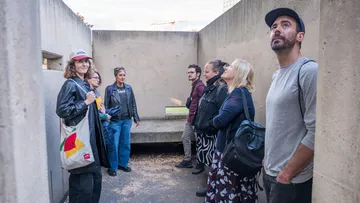 People standing, looking upwards, concrete room.