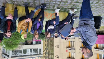 Group sitting outdoors on a wall listening.