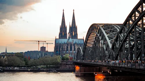 Kathedrale mit Brücke über Fluss bei Sonnenuntergang.