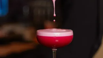 Red cocktail with pink foam topping.