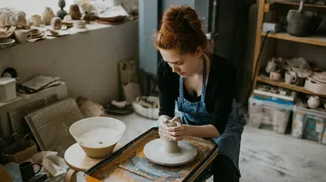 Woman potting clay in a workshop.