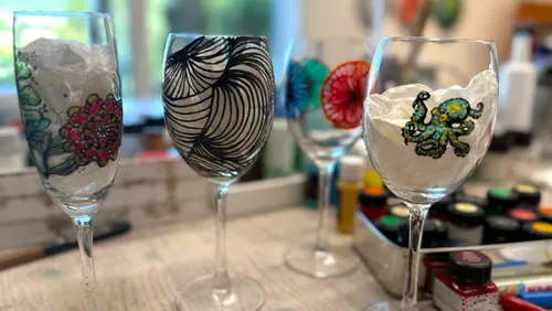 Weingläser mit künstlerischen Designs auf Tisch.