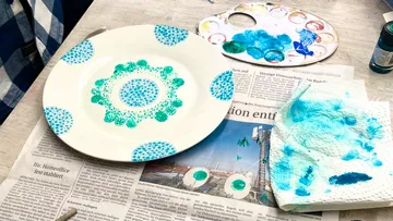 Plate decorated with blue-green dots, newspaper background.