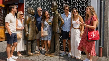 Group touring with guide by statues outdoors.