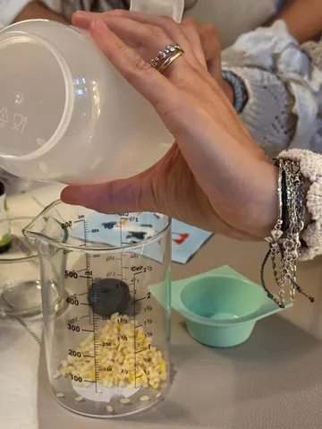 Hand pouring seeds into measuring cup.