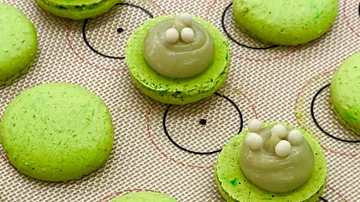 Grüne Macarons auf Backmatte mit Füllung.