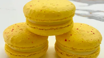 Three yellow macarons on table.