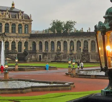 Brunnen im Hof mit prunkvollem Gebäude.