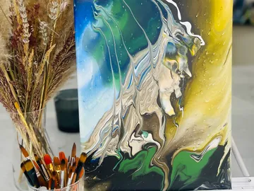 Colourful painting stands next to brushes and dried flowers.