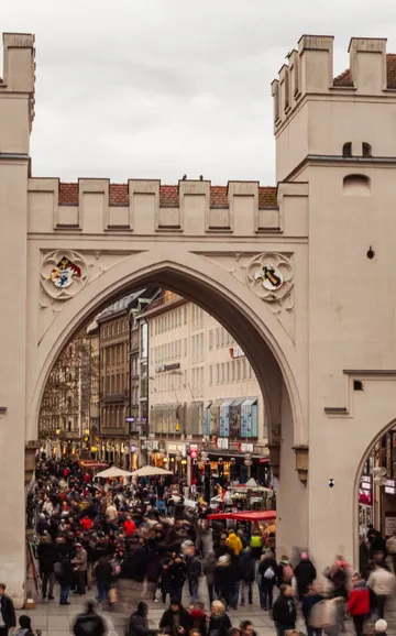 Menschenmenge geht unter historischem Stadttor durch.