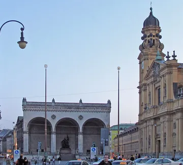 Street with cars, historical buildings, people walking.