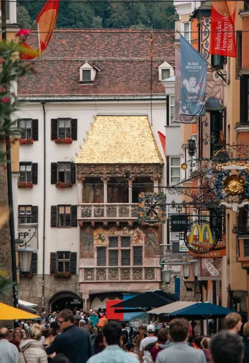 Menschenmenge läuft unter Goldenem Dach, historische Stadt.