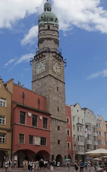 Uhrturm steht auf belebtem Stadtplatz.