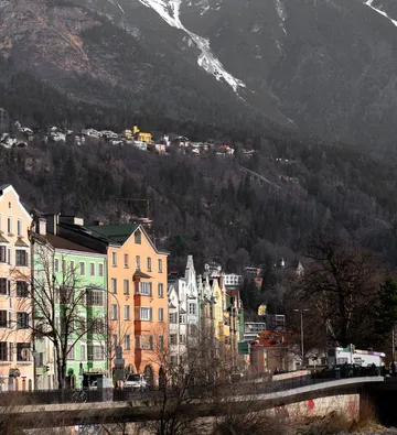 Bunte Häuser an Straße neben Berghang.