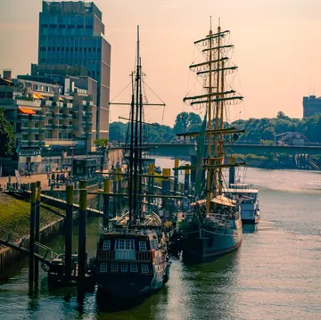 Segelschiffe am urbanen Flussufer angedockt.