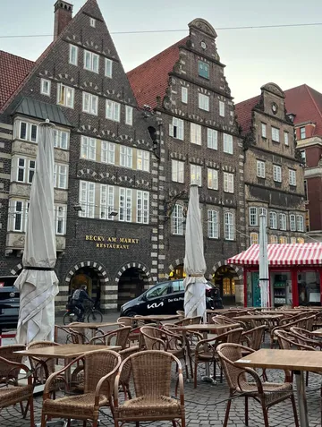 Café chairs, tables in front of historic buildings.