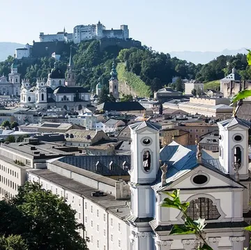 Castle overlooking city with mountains beyond.
