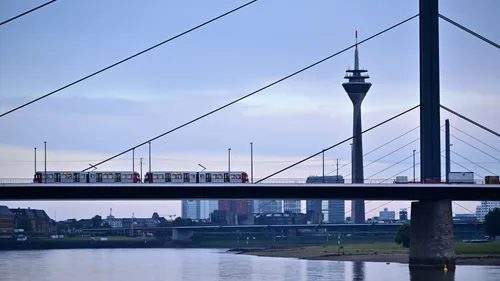 Zug überquert Brücke über Fluss mit Turm.