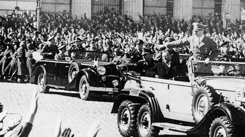 Autos im Umzug, Menschen jubeln.
