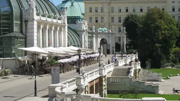 Historisches Gebäude mit Straßencafé, sonniger Tag.