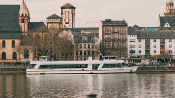 Boat sailing on river beside historic buildings.