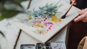 Hands painting abstract watercolors on paper.