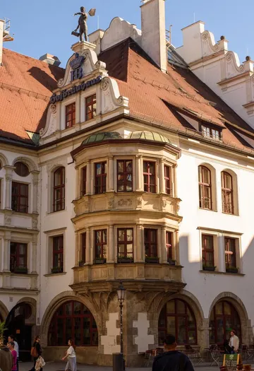 Historic German building with red windows, statue on rooftop.