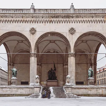 Statuen in Rundbögen, verschneiter öffentlicher Platz.