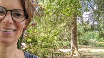 Woman smiling, standing in forest